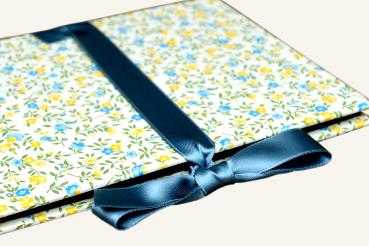 Leporello open with light pages, yellow flower cover and yellow satin bow